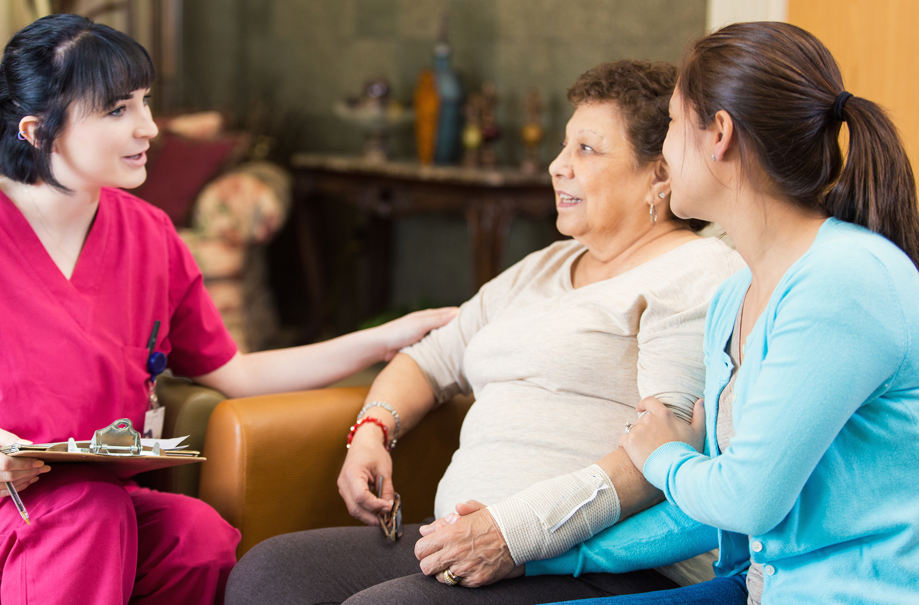 A nurse at the New Jewish Home talks with a Hispanic female patient about her diagnosis as her granddaughter listens along